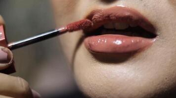Close up shot of a woman applying lip gloss for a shiny, beautiful look. Focus on the glossy texture and detail on her lips. video