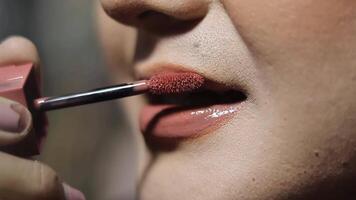 Close-up of a woman applying lip gloss to her lips. The focus is on the applicator and the glossy texture of the product, beauty concept. video
