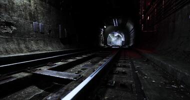 Dark underground tunnel with railroad tracks and distant light source video
