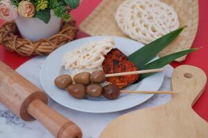 Traditional Indonesian Dish with Grilled Chicken, Quail Eggs Skewers, Rice, and Crispy Crackers photo