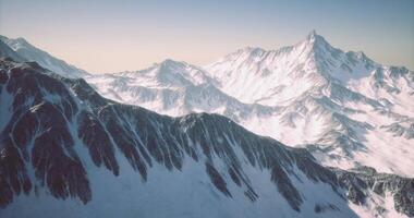 Snow covered mountain range in a serene landscape during daylight hours video