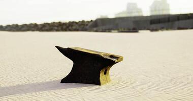 Blacksmith anvil resting on a sandy surface with a distant urban backdrop video