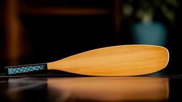 Close-up view of a wooden paddle resting on a dark surface with a blurred background photo