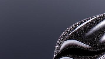 Close-up view of glossy black abstract shape against a smooth dark background, showcasing texture photo
