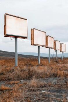 A series of billboards stretch across a desolate area, each displaying identical advertising content. This visual repetition continues into the distant horizon, emphasizing consumer presence photo