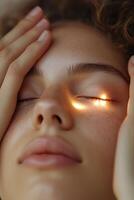 A person rests peacefully with closed eyes, their forehead supported by hands made of soft, glowing light, symbolizing care and soothing relief from discomfort photo