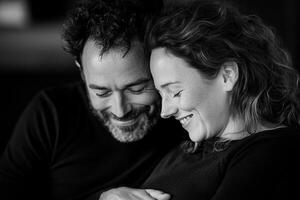 The father-to-be rests his head on the mother's belly, laughing softly as he feels the baby kick. The softly blurred background enhances their intimate connection photo