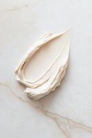 Creamy skincare swatch elegantly displayed on a marble surface, illuminated by soft lighting that enhances its rich texture and velvety consistency, creating an artistic effect photo