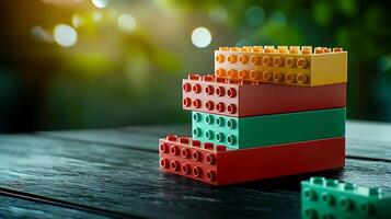 Colorful building blocks arranged on a wooden surface with a blurred green background photo
