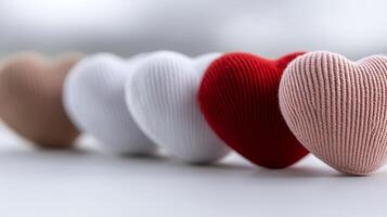 Colorful knitted hearts arranged in a row, symbolizing love and unity against a soft background photo