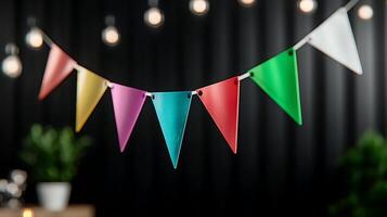 Colorful triangular bunting flags hanging against a dark background with string lights and greenery photo
