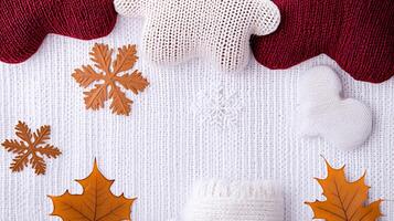 Cozy autumn-themed flat lay featuring knitted elements, leaves, and snowflakes on a textured background photo