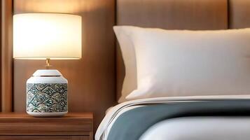 Cozy bedroom scene featuring a decorative lamp on a nightstand beside a neatly made bed photo