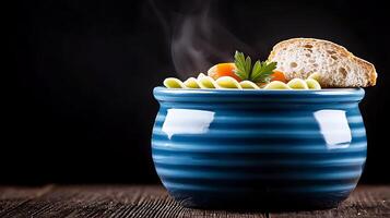 Steaming bowl of pasta with vegetables and bread on a wooden table against a dark background photo