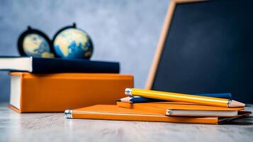 Study materials including notebooks and pens on a desk with a globe and chalkboard in the background photo