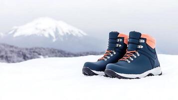 Stylish winter boots on a snowy landscape with a mountain backdrop under a cloudy sky photo