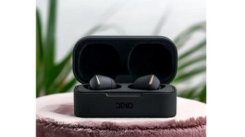 Stylish wireless earbuds in a sleek charging case on a plush surface with greenery in the background photo