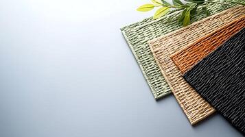 Textured placemats in various colors arranged neatly with a green leaf accent on a light background photo