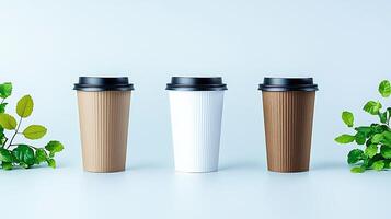 Three coffee cups in various colors arranged on a light background with green leaves photo