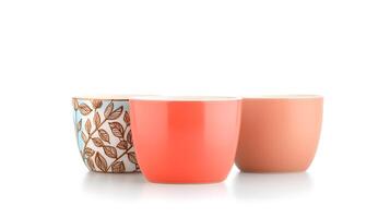 Three colorful ceramic cups with floral patterns and solid colors on a clean white background photo