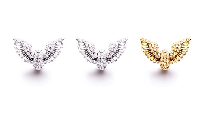 Three intricately designed wing-shaped jewelry pieces in silver and gold on a clean background