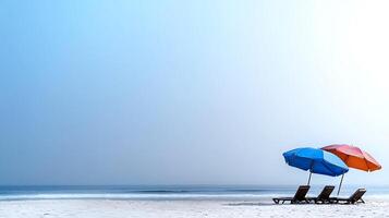 Two colorful beach umbrellas with lounge chairs on a serene beach under a clear sky photo