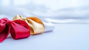 Two elegant satin ribbons in red and gold resting on a soft surface with a blurred background photo
