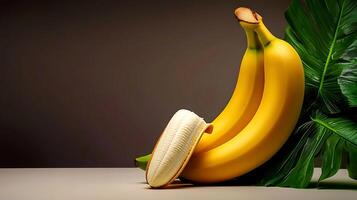 Two ripe bananas beside a large green leaf on a neutral background, showcasing freshness and vitality photo