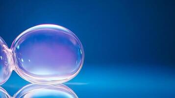 Two translucent soap bubbles resting on a reflective surface against a blue backdrop photo