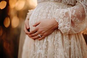 In a serene setting, a pregnant woman cradles her belly gently, surrounded by warm golden light. The soft blur in the background enhances the connection and intimacy of the moment photo