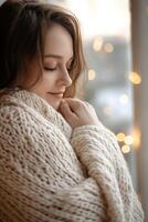 A pregnant woman radiates tranquility while wrapped in a soft knit sweater. Natural light enhances her serene expression against a beautifully blurred backdrop, creating a cozy atmosphere photo