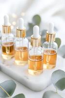 Four glass droppers filled with golden herbal extracts are elegantly arranged on a marble tray alongside fresh eucalyptus leaves. The soft lighting enhances the premium feel of the display photo