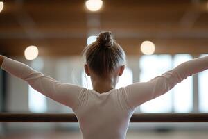 A young girl skillfully balances on a beam, arms extended and posture elegant, in a softly lit gym that captures the energetic atmosphere of the space photo
