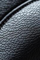 The composition showcases a soft-focus black leather texture, featuring delicate raised stitching. This elegant backdrop serves as a perfect canvas for branding text and design elements photo