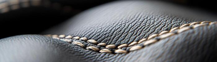 Soft-focus black leather surface features intricate raised stitching that adds a touch of sophistication, making it ideal for luxury branding applications or design projects photo