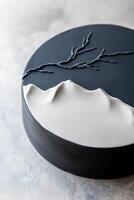 Smooth black and white cake showcases subtle embossed mountain details and delicate branches, perfect for celebrations. This design emphasizes elegance and sophistication at any gathering photo