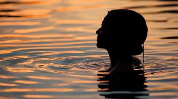 Silhouette of a woman in the water at sunset photo