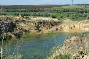 a huge blue lake in a quarry. deciduous forests and fields around. the horizon is visible. an artificial lake among fields photo