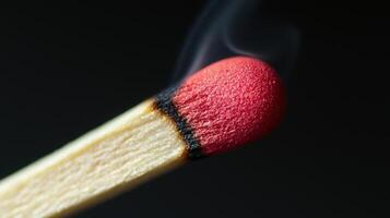 A matchstick ignites with a bright flame, producing smoke that curls upwards against a dark background, capturing a moment of combustion and energy photo