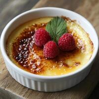Creamy dessert topped with caramelized sugar and fresh raspberries, served in white ramekin. delightful treat for any occasion photo