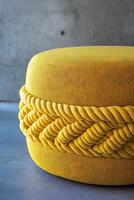 Bright yellow round pouf with woven rope design, perfect for modern decor. This stylish piece adds pop of color and texture to any indoor or outdoor space photo