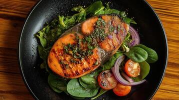 plate of food with a large piece of salmon on it. The salmon is cooked to a golden brown color and appears to be seasoned with herbs and spices photo