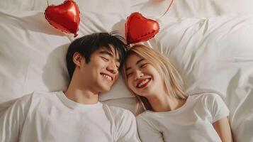 Asian young couple lying in bed together. The man is lying on his back with his head resting on the woman's shoulder. photo