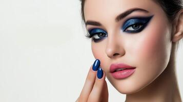 close-up portrait of a woman's face. The woman has dark hair styled in a sleek updo and her makeup is done in a dramatic style with dark blue eyeshadow photo