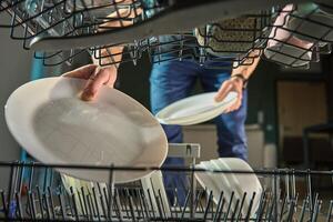 Man loading plates into dishwasher photo