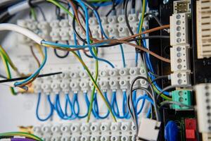 Colorful wires and components connected to terminal block in distribution box. Electrical circuit board with wiring and connections photo