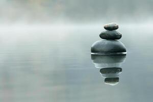 Smooth stones stacked in balance on calm water. Concept of tranquility and harmony photo