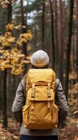 A woman with a yellow backpack walking through a forest photo