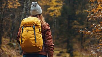 A woman with a yellow backpack walking through the woods photo