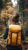 A woman with a yellow backpack walking through a forest photo
